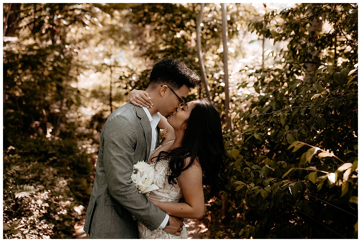 newlyweds kiss in wooded area by Brea Warren Photo