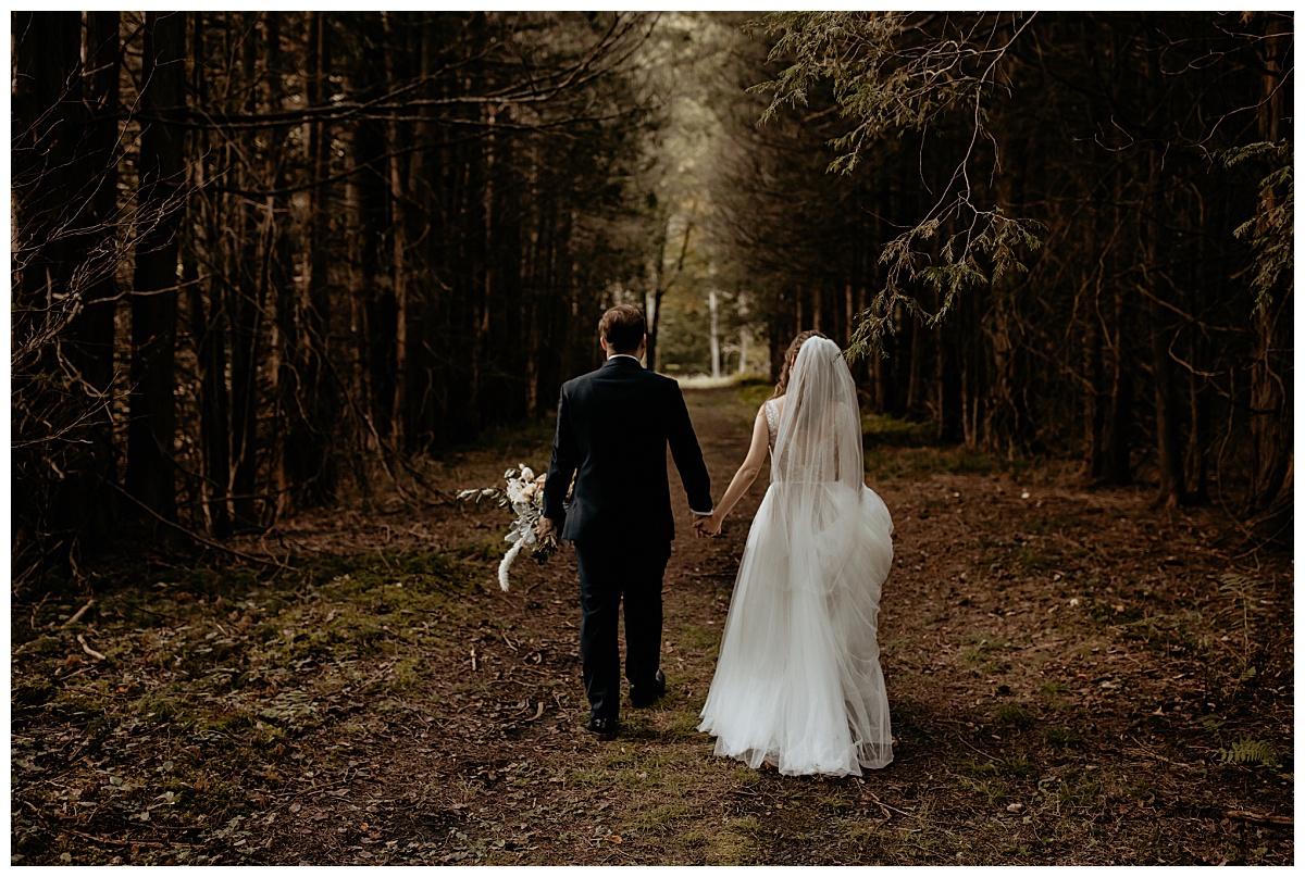 newlyweds hold hands as they walk into enchanted forest together by Brea Warren Photo